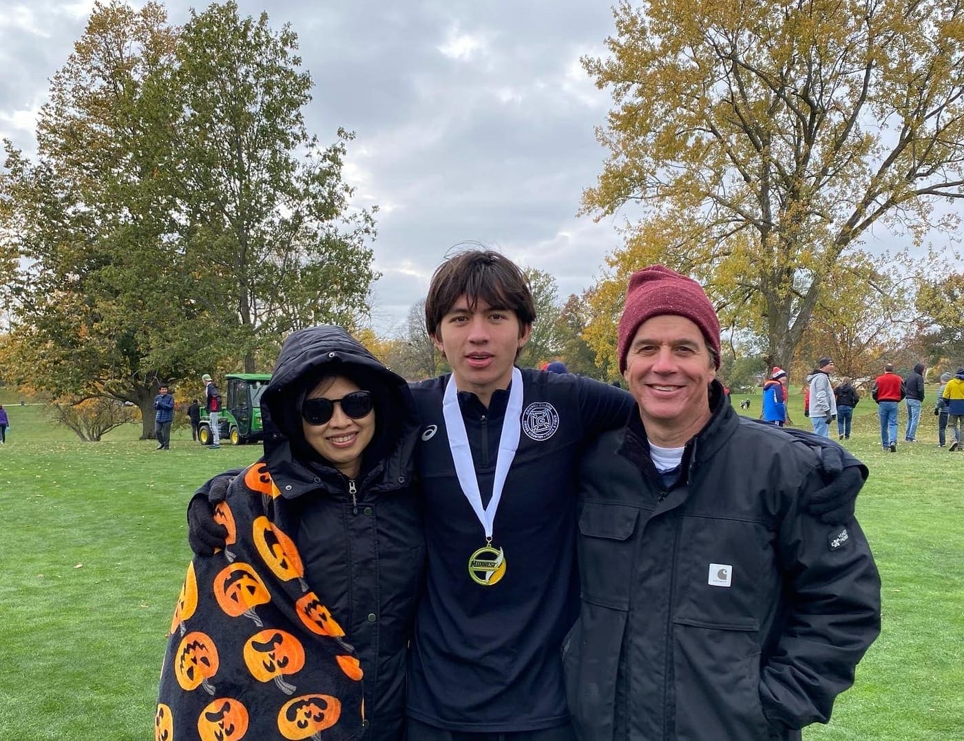 Connor wearing a cross country medal with his parents